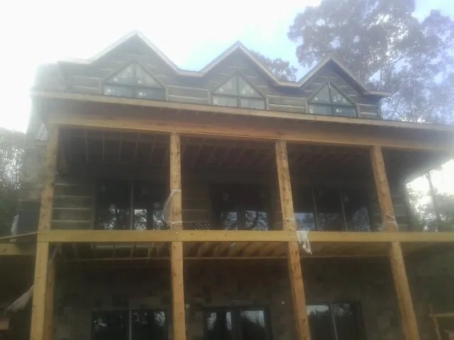 Dormers and porch framing on a large log home under construction — Roof Coating work by our crew in Piermont