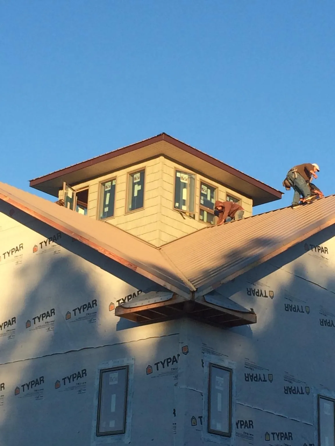 Roofers working around a rooftop cupola on a new metal roof at sunset — Roof Waterproofing in Piermont by Roofing Brothers